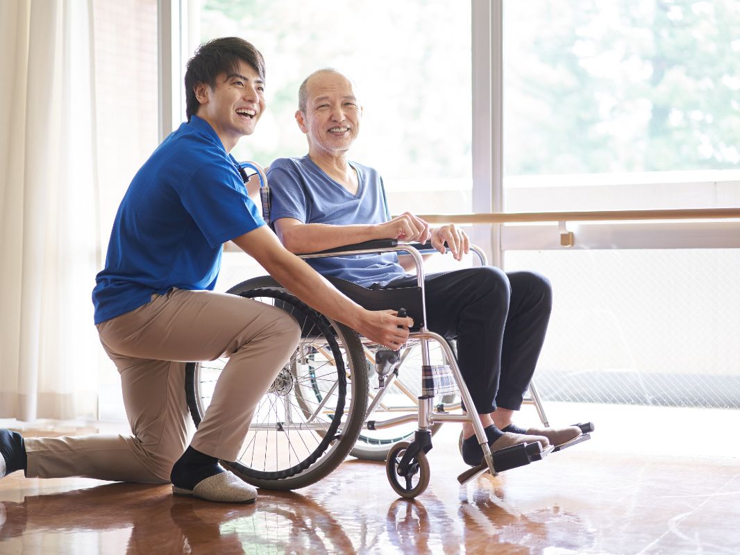 Hombre junto a persona mayor en silla de ruedas sonriendo